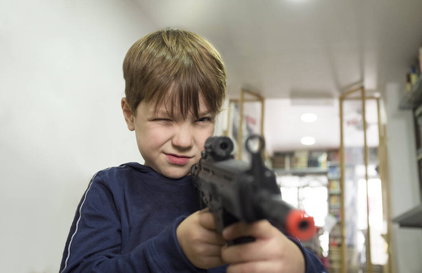 Pětiletý chlapec si hraje s útočnou puškou. Koncept hraček. Selektivní zaměření - Fotografie, Obrázek