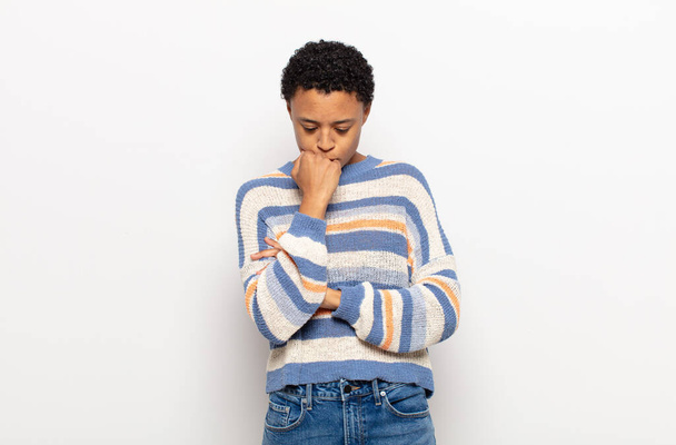 afro young black woman feeling serious, thoughtful and concerned, staring sideways with hand pressed against chin - Foto, Imagen