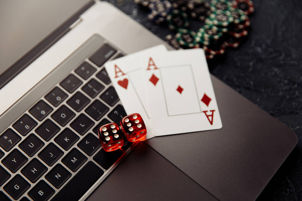 Žetony, červené kostky a hrací karty s esa pro poker on-line nebo kasino hazardní hry na klávesnici notebooku horní pohled. Online kasino koncept - Fotografie, Obrázek