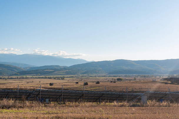 Personenansicht gelbe landwirtschaftliche Felder Ernte neben Solaranlage Kopierplatz für Text bulgarische Berge Tech Garben Heu auf Feld verstreut - Foto, Bild