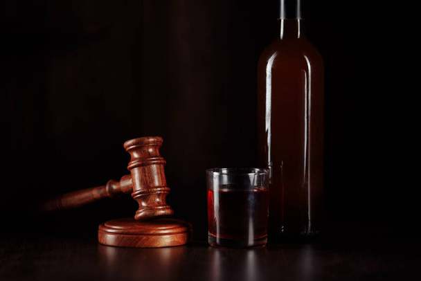 Bottle and glass with whisky and judge gavel, alcohol and crimes concept - Photo, Image