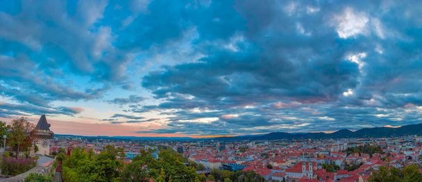 Paisaje urbano de Graz y la torre del reloj, famosa atracción turística en la colina de Schlossberg, Graz, región de Estiria, Austria, al atardecer. Cielo dramático, vista panorámica - Foto, imagen