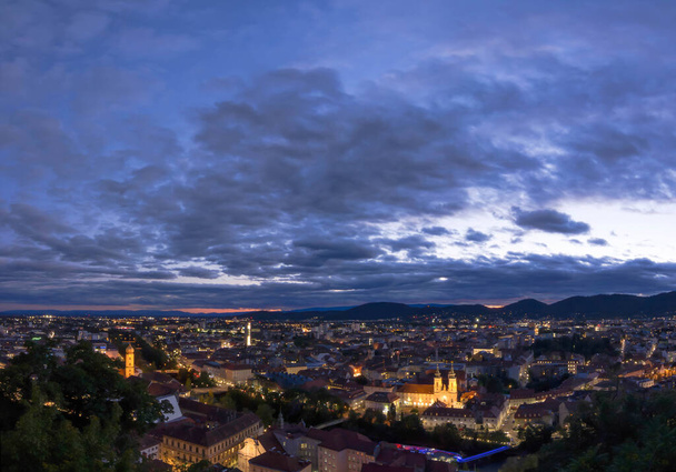 Graz és Mariahilfer város fényei templom, kilátás a Schlossberg dombról, Graz, Stájerország, Ausztria, naplemente után. Panorámás kilátás. - Fotó, kép