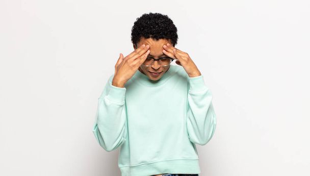 young afro woman looking stressed and frustrated, working under pressure with a headache and troubled with problems - 写真・画像
