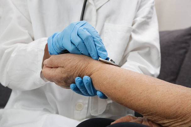 Medizinisches Personal benutzt Stethoskop, um die Pulsfrequenz eines älteren Patienten zu untersuchen. Gesundheits-Check. - Foto, Bild