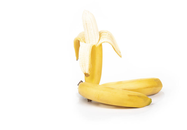 Strzelanina w studio. Gałąź dojrzałych żółtych bananów w skórce. Na białym tle. Zbliżenie - Zdjęcie, obraz