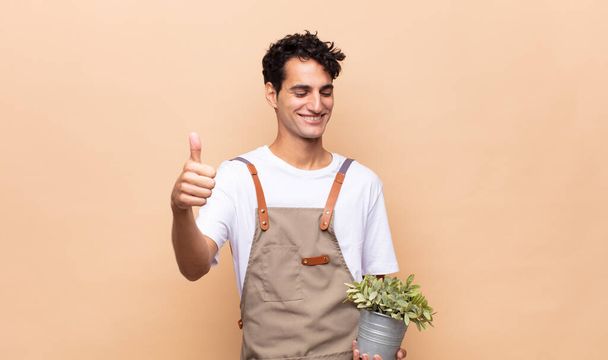 young gardener man feeling proud, carefree, confident and happy, smiling positively with thumbs up - Photo, Image