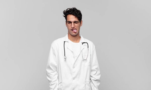young physician with cheerful, carefree, rebellious attitude, joking and sticking tongue out, having fun - Φωτογραφία, εικόνα