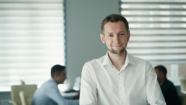 Portret van een vrolijke kantoormedewerker kijkend naar camera in modern kantoor, positieve mannelijke werknemer met een lachend gezicht tevreden met een goede loopbaan - Video