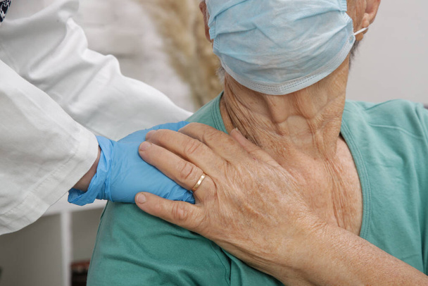 Porträt einer älteren kaukasischen Frau mit medizinischer Schutzmaske. Betreuung älterer Menschen während des Coronavirus-Ausbruchs, eine helfende Hand, häusliches Pflegekonzept. - Foto, Bild