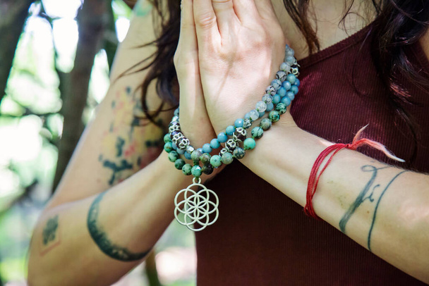 Mains féminines faisant namaste pratique du yoga mudra dans la forêt avec collier mala - Photo, image
