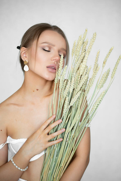 Beautiful woman in underwear with ears of wheat in hands on a white background. - Foto, Bild