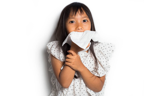 Ázsiai kislány fújja az orrát, elszigetelt fehér háttér - Fotó, kép