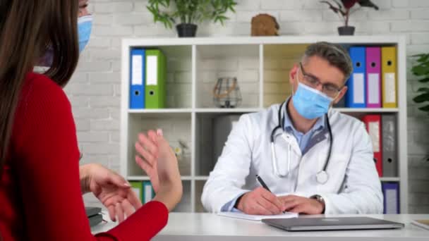 Femme en masque médical de protection parle de problèmes de santé gestes avec les mains - Séquence, vidéo