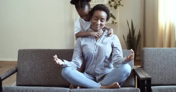 Active preschool african daughter tickles ethnicity mother sitting in lotus position practice self-control feel serenity calmness, reduce stress fatigue during day at home with little mixed race child - Footage, Video