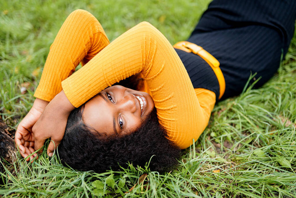 Carina donna africana sdraiata sull'erba in un parco - Foto, immagini