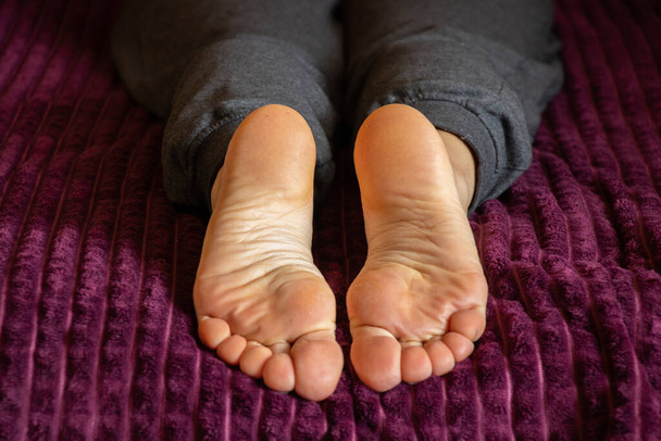 γυναικεία γυμνά πόδια στο κρεβάτι στην κρεβατοκάμαρα, αναπαύονται στο κρεβάτι - Φωτογραφία, εικόνα
