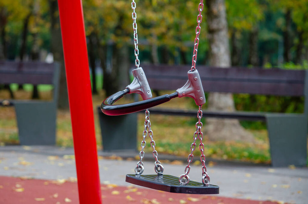 On a sunny day, the children's swing is empty on the playground. - Photo, Image