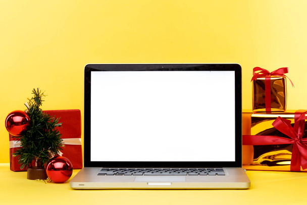 Online karácsonyi vásárlási koncepció a laptop kijelzőn. Fehér képernyő a számítógépen, és ajándékok papírzacskók közelében. - Fotó, kép