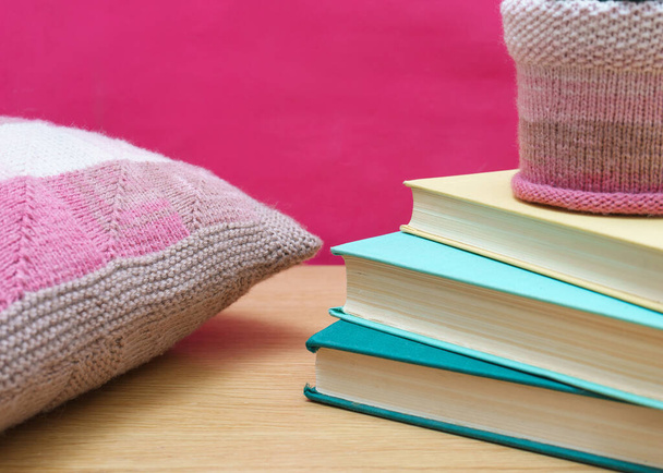 Old books on a wooden shelf pink background and knitted decorative pillow. home decor - Foto, Imagem