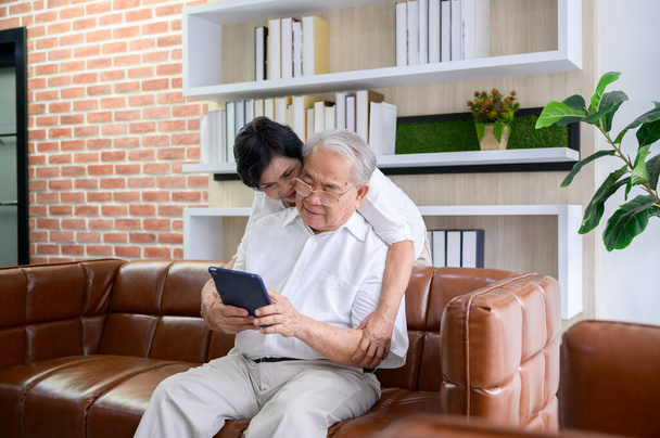 A happy senior Asian couple is using tablet and talking with family on webcam at home, retirement concept. - Foto, Imagem