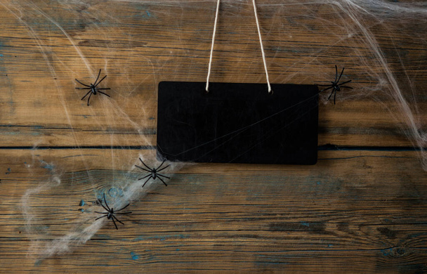 Am Spinnennetz hängt eine leere Tafel. Nahaufnahme von niedlichen Halloween-Dekorationen. - Foto, Bild