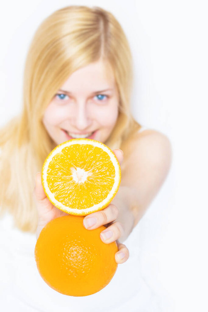 Młoda blondynka trzyma pomarańczowy owoc i uśmiecha się, zdrowe jedzenie i organiczne piękno - Zdjęcie, obraz