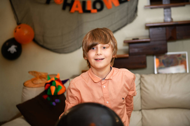 хлопчик розважається і грається з помаранчевими і чорними кульками Хеллоуїна. Діти готуються до святкування Хеллоуїна вдома, прикрашають будинок
 - Фото, зображення