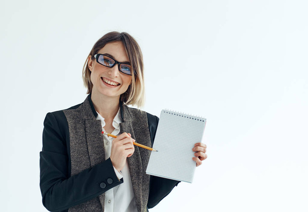 Une femme avec un cahier et un stylo dans ses mains sur un costume de finance d'entreprise de fond léger - Photo, image
