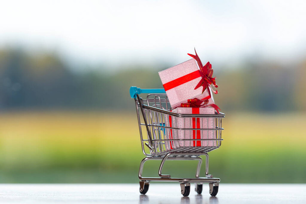 shopping cart with presents on blurred background,  Christmas shopping concept - Фото, изображение