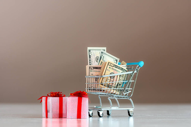 Christmas expense planning concept , gift boxes and shopping cart full of money - Foto, Bild