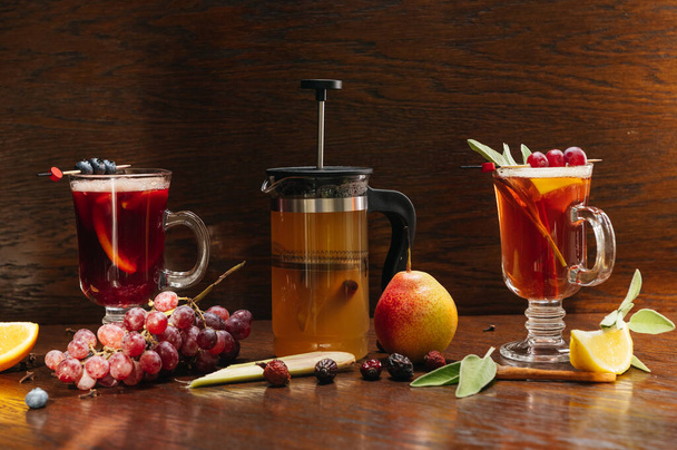 Various autumn or winter seasonal alcohol hot cocktails. Blueberry mulled wine, tea with pear and rose hips, grog with lemon and cinnamon on the table in restaurant - Foto, Imagem