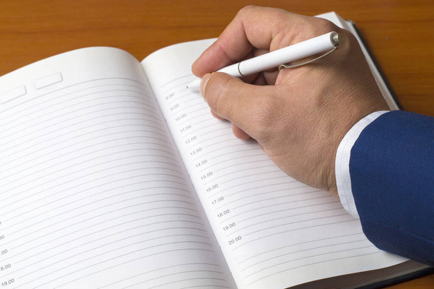 Крупним планом рука людини пише в щоденнику. Бізнесмен планує робочий день. Управління часом, план дій
. - Фото, зображення
