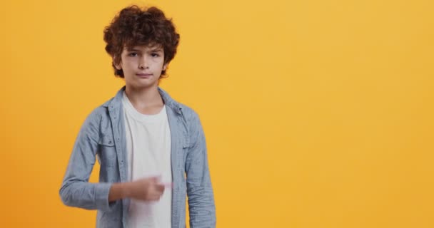 Μεγάλη promo. Συναισθηματική αγόρι gesturing στην άκρη, δείχνοντας χώρο αντίγραφο πάνω από πορτοκαλί φόντο - Πλάνα, βίντεο