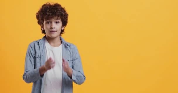 Verrast jongen schreeuwen en aanraken van zijn wangen in verbazing, cant geloven, oranje studio achtergrond met lege ruimte - Video