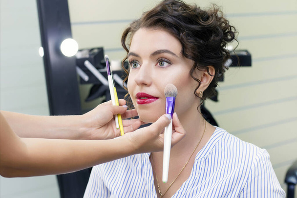Make up artist applies a light layer of matte powder using a professional makeup brush. girl at makeup artist - Foto, Imagen