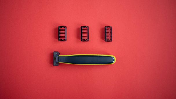 Beard trimmer with three attachments on the red background.  - Foto, Imagem