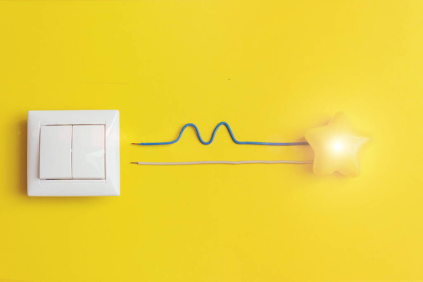 interruptor blanco y estrella brillante amarilla con fase de cables, cero, tierra, concepto de singularidad. Idea, innovación, concepto de creatividad - Foto, Imagen