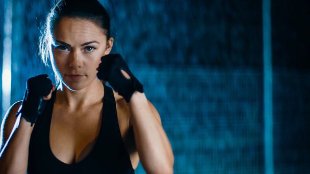 Beautiful Sporty Fitness Girl is Doing Sharowboxing Exercises. She is Ready to Punch. Night in Heavy Rain with One Light Behind Her. - Foto, Bild