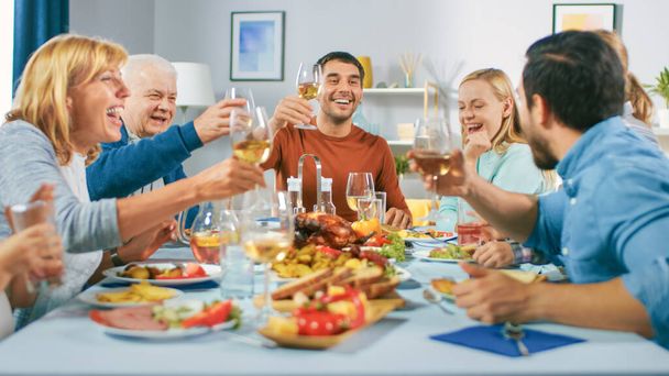 家庭での家族や友人のお祝い、子供の多様なグループ、若い大人と高齢者がテーブルに集まって楽しい会話をしています。メガネをかけトーストを作る. - 写真・画像