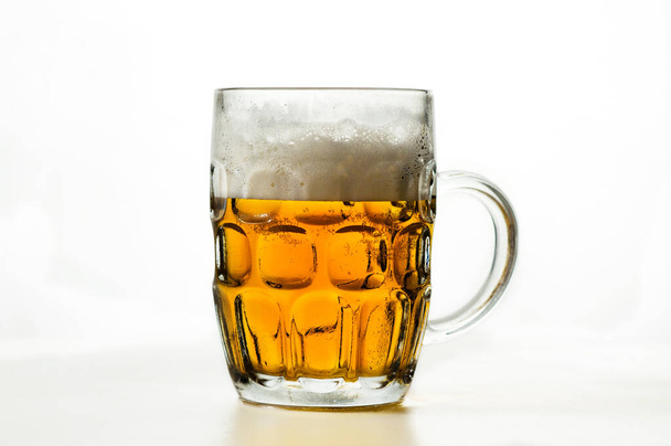 透明なガラスの中に泡立つビールと白い背景にポテトチップスの山 - 写真・画像