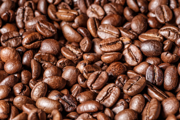 Freshly roasted coffee beans background.Dark roasted coffee beans with scoop on wooden background. - Foto, immagini