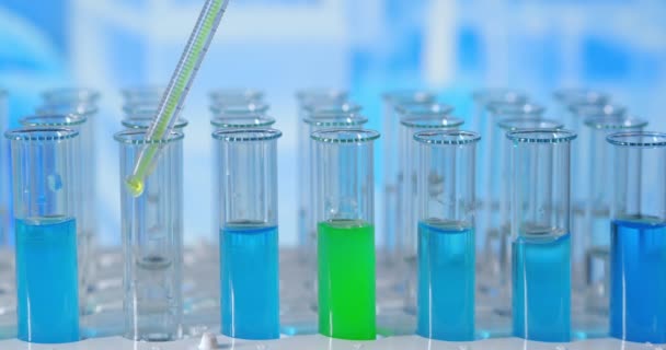 Dans un laboratoire, un scientifique muni d'une pipette analyse un liquide coloré pour extraire l'ADN et les molécules dans les éprouvettes. Concept : recherche, biochimie, nature, médecine pharmaceutique - Séquence, vidéo