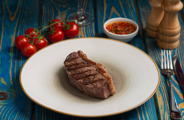 Grilled steak ,cherry tomatoes salt and pepper on wooden table. - Фото, зображення