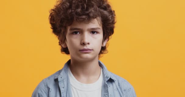 Αξιολάτρευτο αγόρι χαμογελά στην κάμερα, στούντιο πορτρέτο πάνω από πορτοκαλί φόντο - Πλάνα, βίντεο
