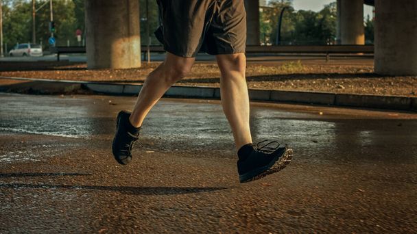 Close up Shot of Muscular Athletic Man Legs Running in the Street. Urban Environment Under a bridge with Cars in the Background. - 写真・画像