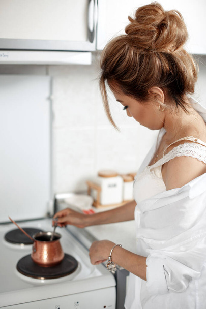 young beautiful Asian girl in beige lace shorts,white shirt preparing morning coffee. selective focus. small focus area. - Photo, Image