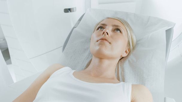 Close-up Portrait Shot of a Female Patient Lying on a CT or PET or MRI Scan Bed, Machine Scans Her Body and Brain. In Medical Laboratory with High-Tech Equipment. - Foto, Imagem