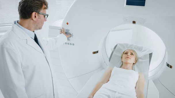 В медицинской лаборатории мужчина-рентгенолог контролирует МРТ или КТ или ПЭТ с помощью женской процедуры. Современное медицинское оборудование. - Фото, изображение
