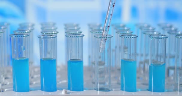 In een laboratorium analyseert een wetenschapper met een pipet een gekleurde vloeistof om het DNA en de moleculen in de reageerbuizen te extraheren. Onderwerp: onderzoek, biochemie, natuur, farmaceutische geneeskunde - Video